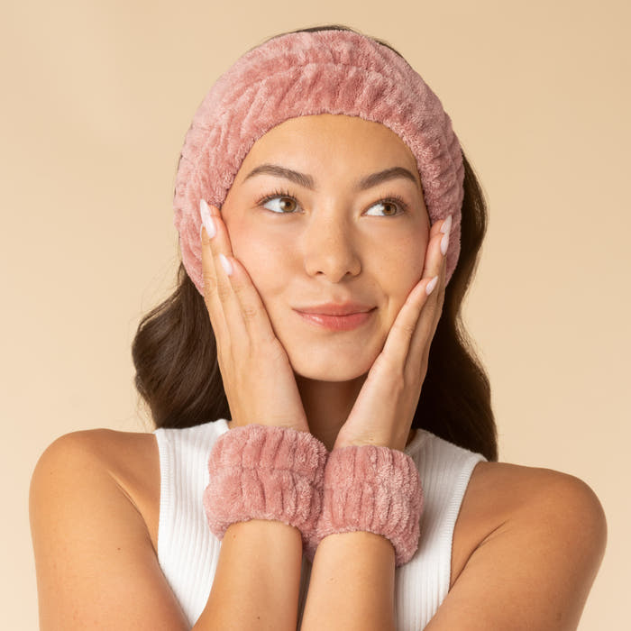 Model using the Terracotta Kitsch Spa Headband and Wristlets 3pc Set while applying skincare products.
