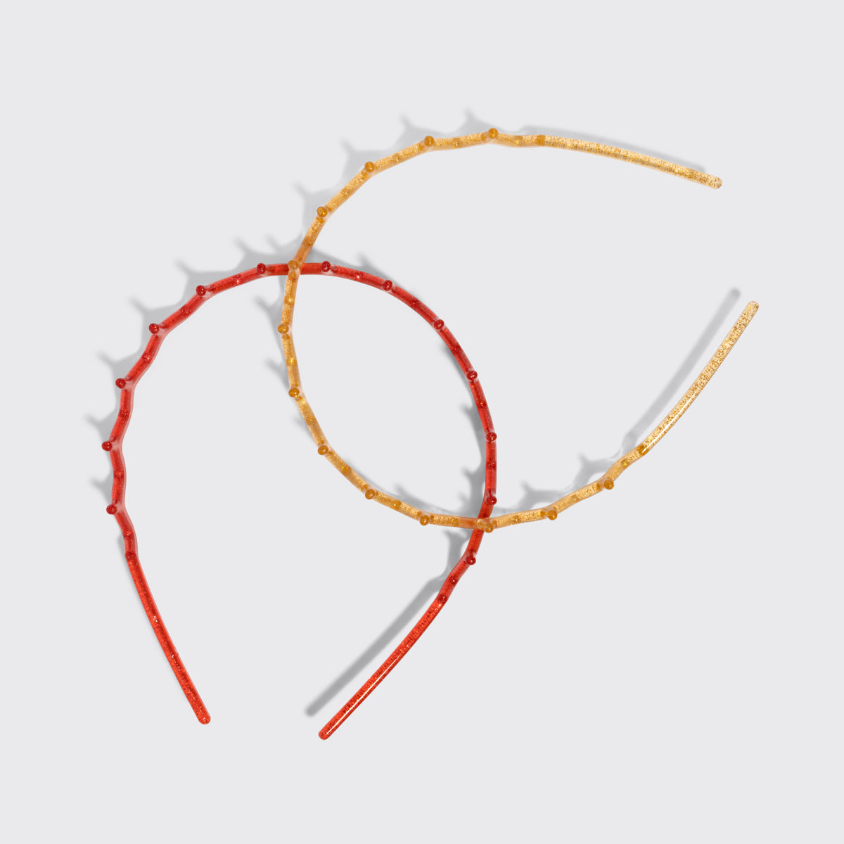 KITSCH Gold & Red Zig Zag Headbands 2pc Set — the gold and red zigzag headbands crossed on a grey background — Helps tame flyaways and loose strands — choosing between the two shades