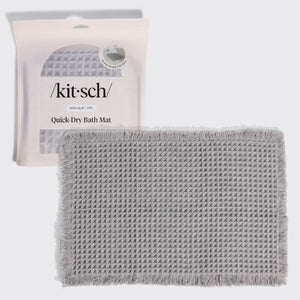 Kitsch Quick-Dry Bath Mat in gray hero image, shown with its retail packaging (non-slip, 1 piece) behind the folded mat.